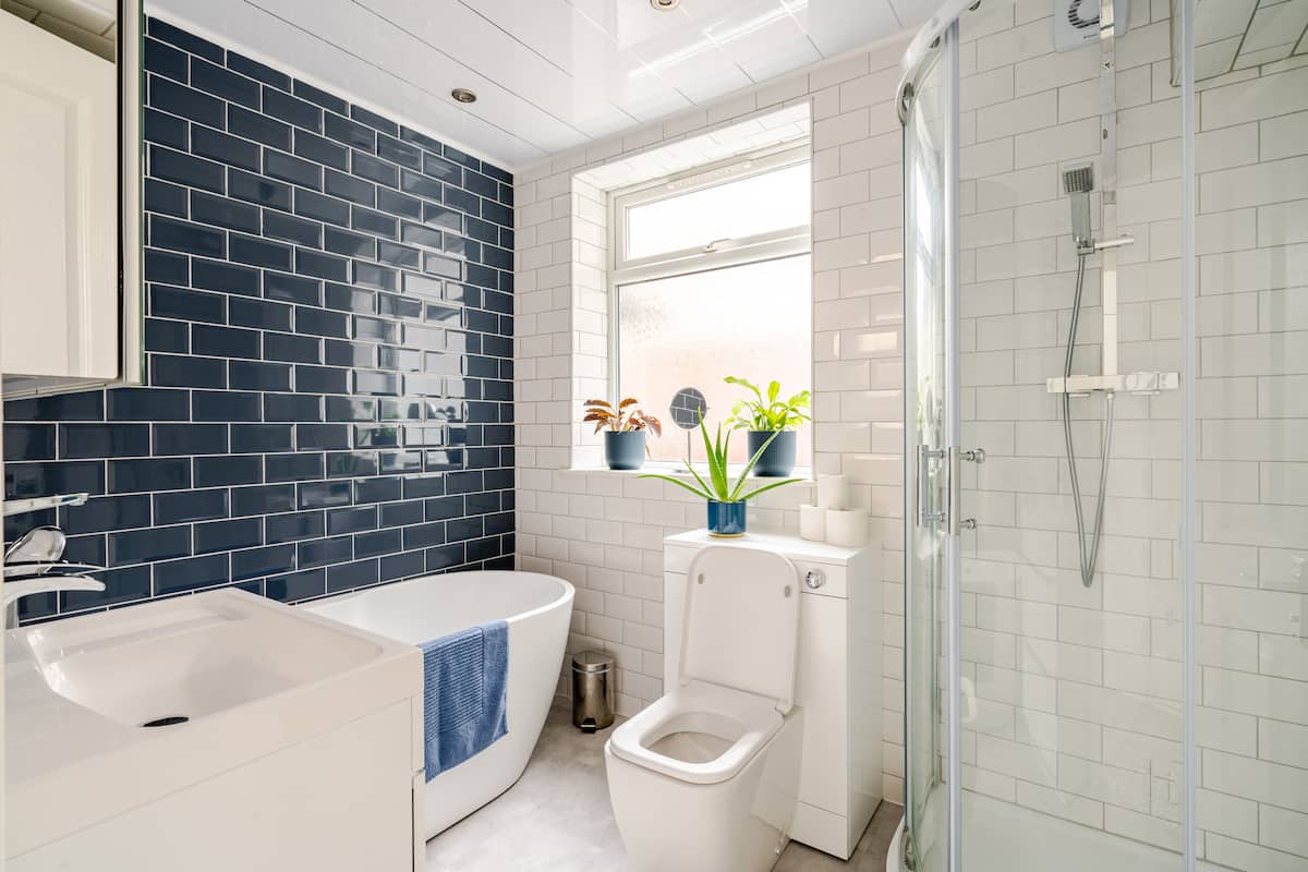 Stylish bathroom with navy tiles, standalone bath and separate shower