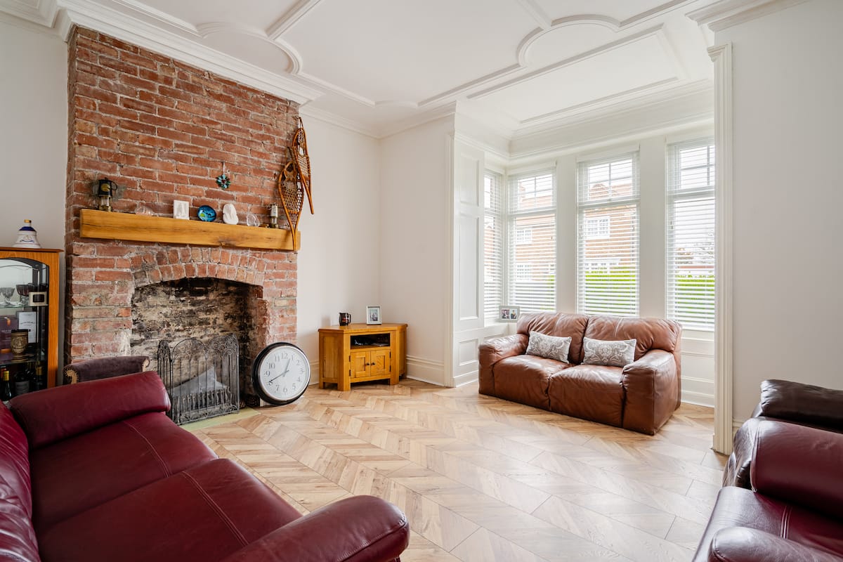 Spacious living room with exposed brick fireplace and herringbone floors