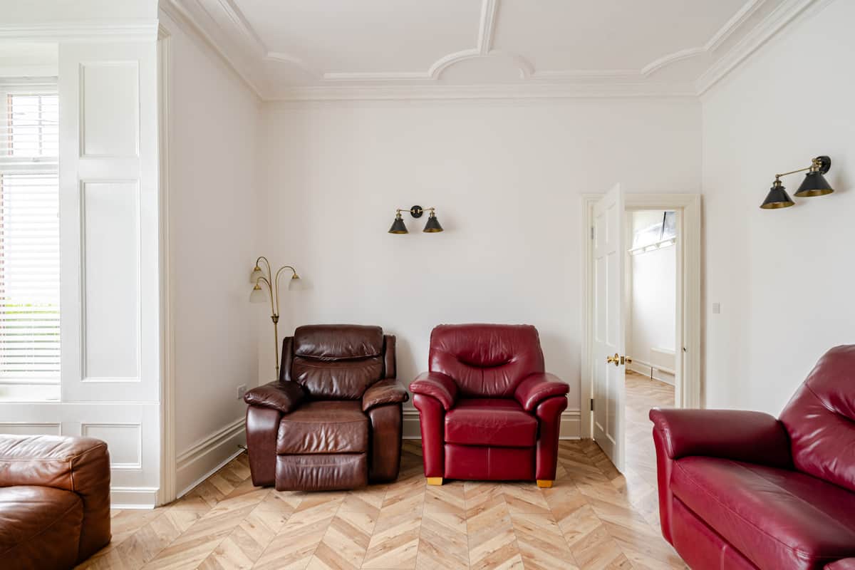 Living room with leather armchairs and period ceiling details